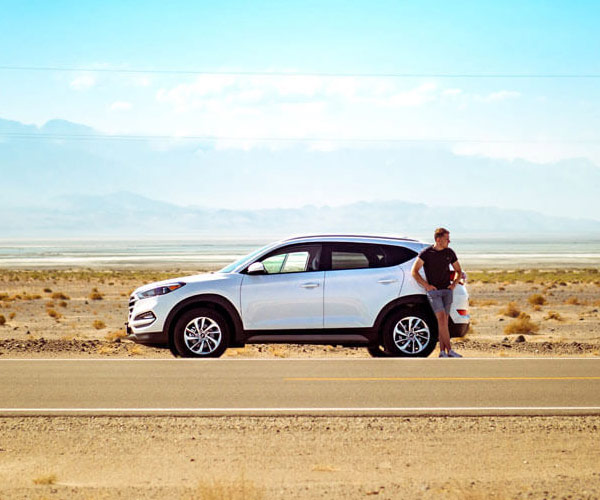 Auto Insurance young man standing on side of road with SUV